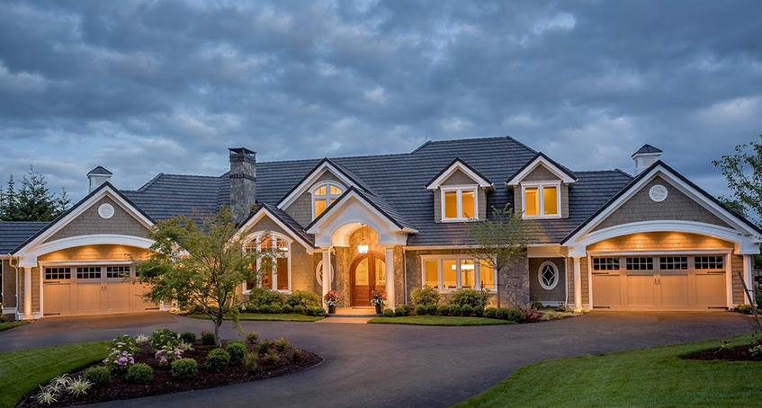 Luxury Home Exterior at Dusk with Warm Lighting and Spacious Driveway
